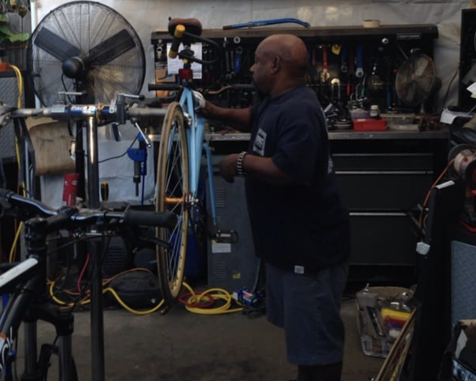 Lance truing a bicycle wheel at the workbench inside the Venice shop